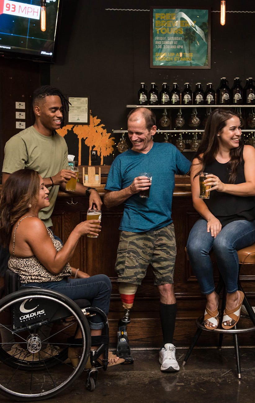 Friends with disabilities enjoying craft beers and socializing in a cozy bar.
