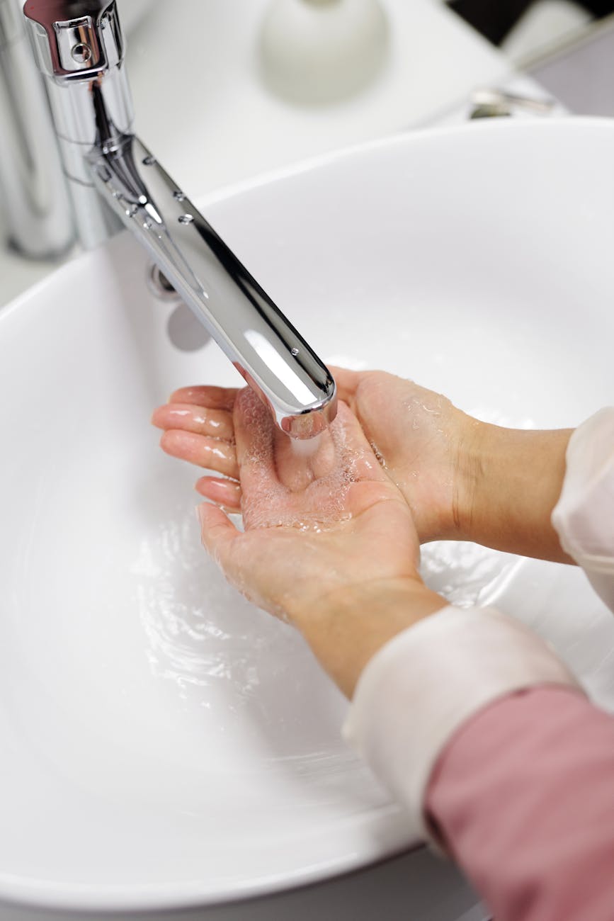 Close-up of hands washing under running water in a modern sink emphasizing cleanliness and hygiene.