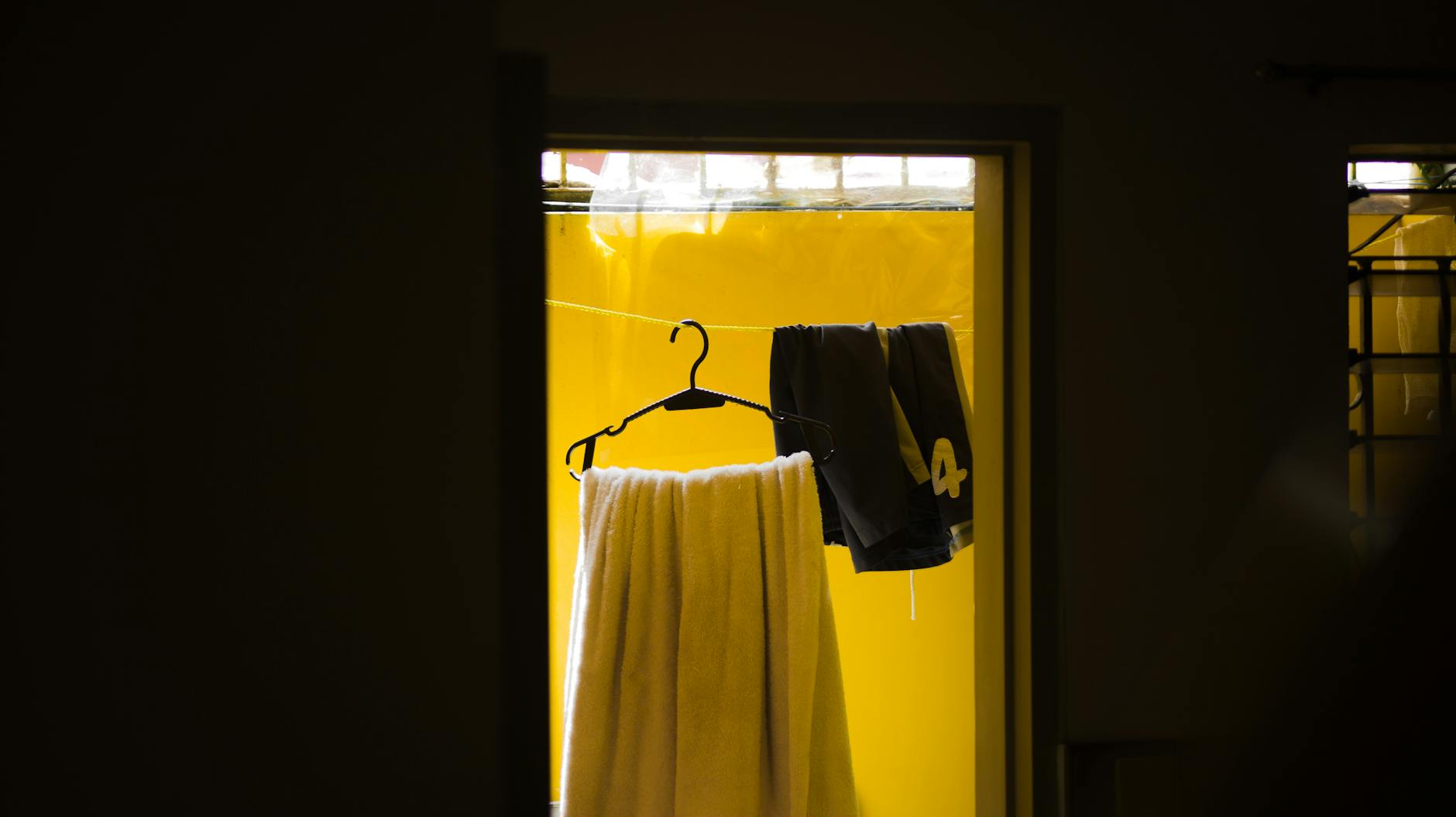 Interior shot of clothes hanging on a line with a vibrant yellow backdrop, creating a cozy household scene.