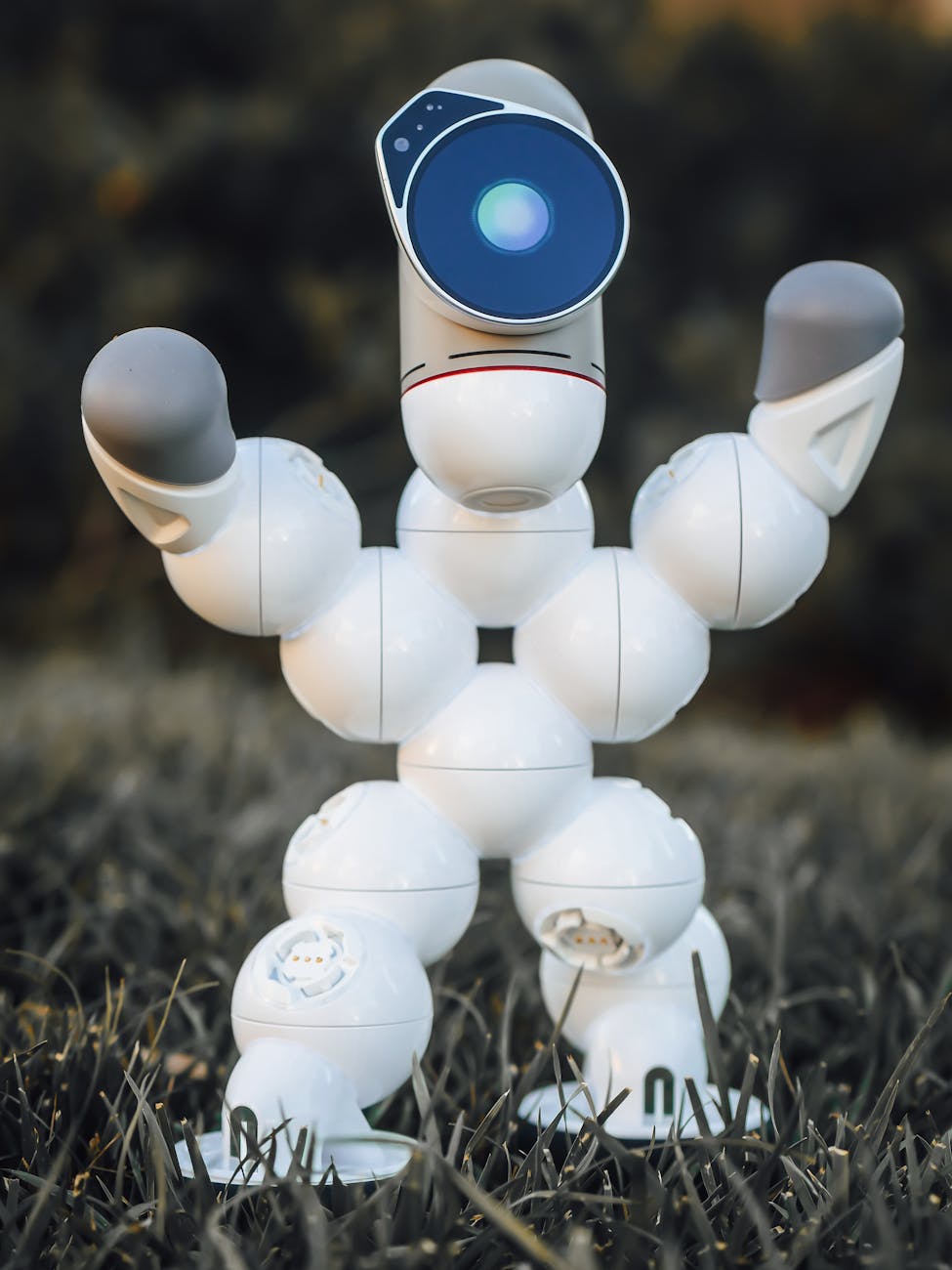 A futuristic robot toy standing on grass, showcasing innovation and technology.