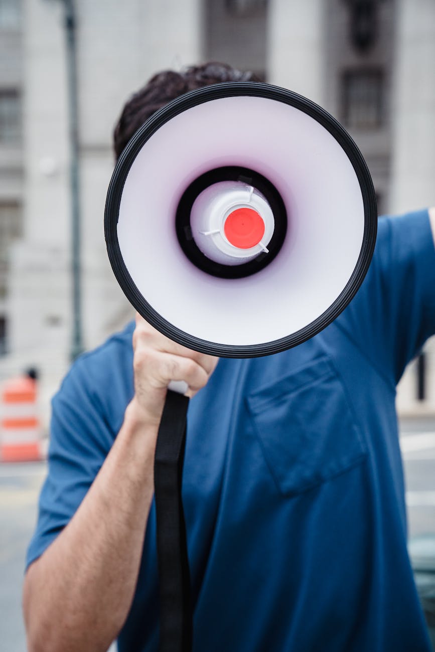 Close-up of a person using a megaphone at an outdoor protest rally.