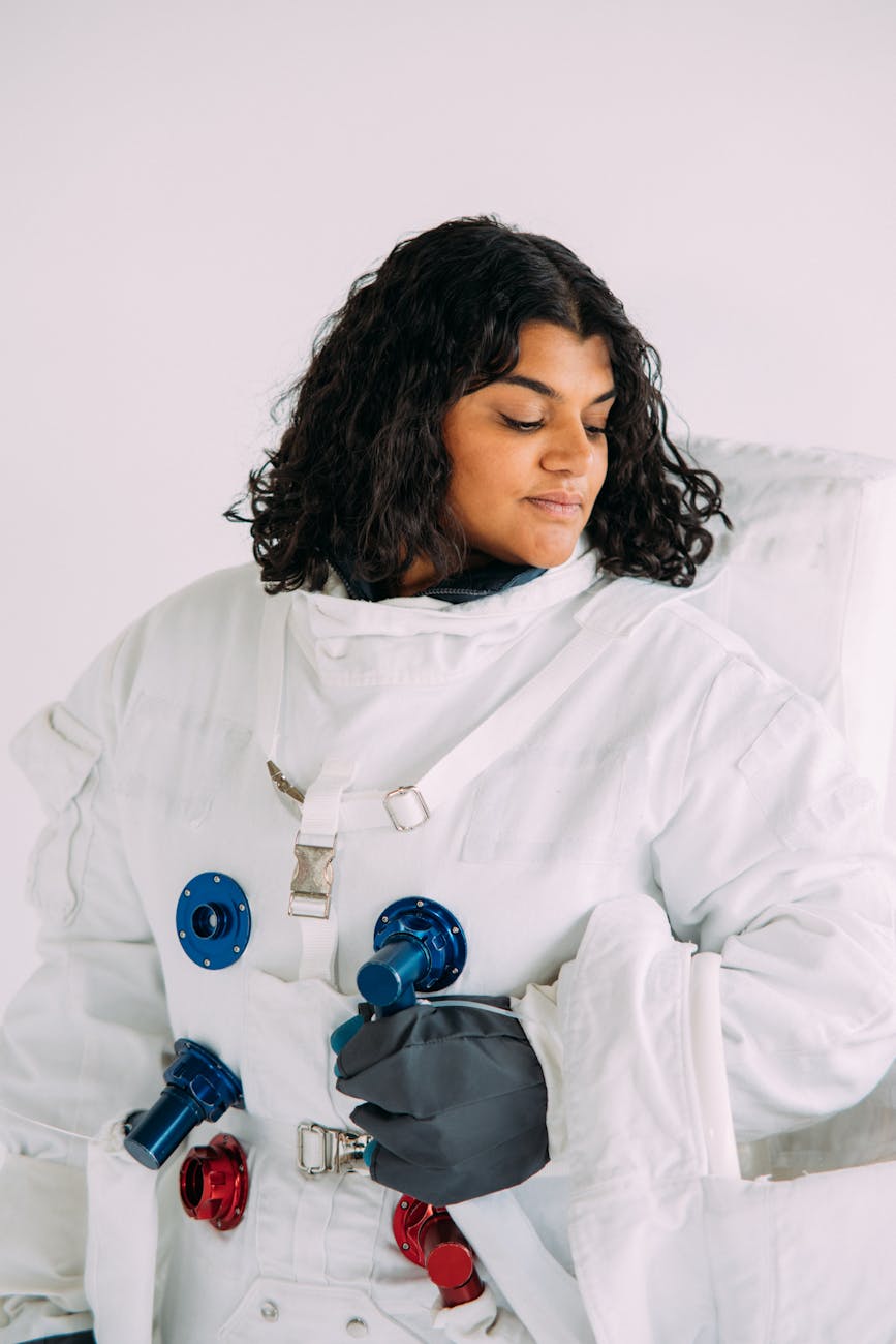 A woman wearing a detailed astronaut costume looks contemplatively to the side.